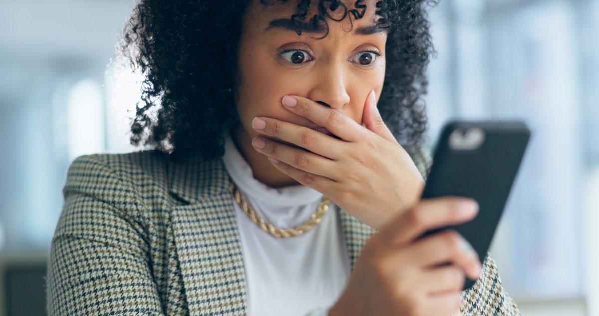 Frau blickt schockiert auf ihr Smartphone