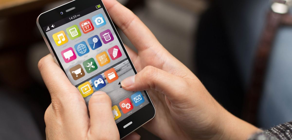 Hände bedienen Smartphone-Bildschirm mit mehreren App-Icons.