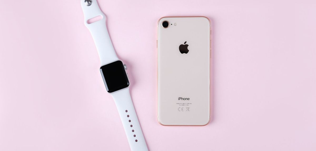 Apple Watch mit iPhone auf rosa Hintergrund