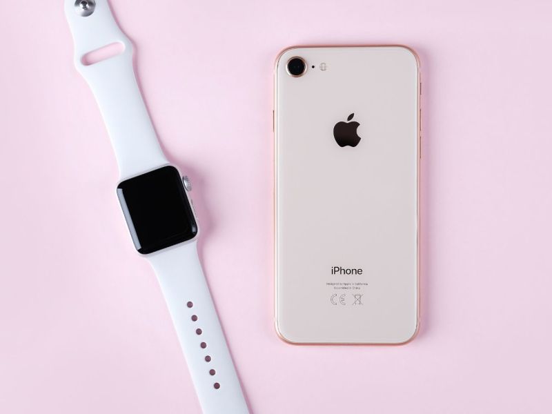 Apple Watch mit iPhone auf rosa Hintergrund