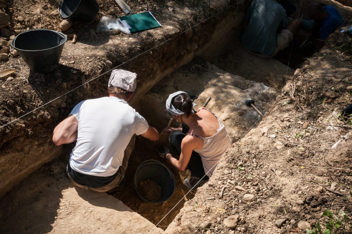 Zwei Archäolog*innen graben an einem archäologischen Fund.