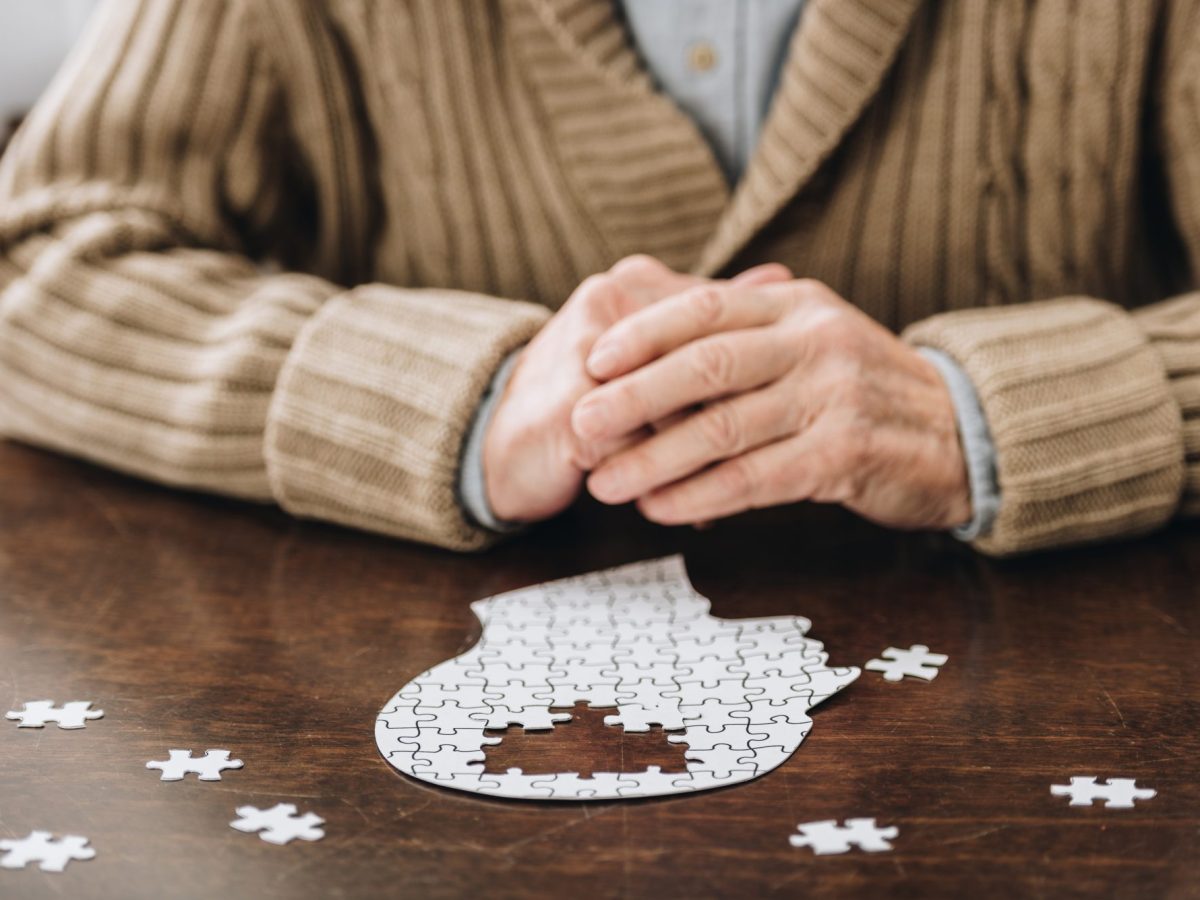 Ältere Mann puzzelt an einem Tisch.