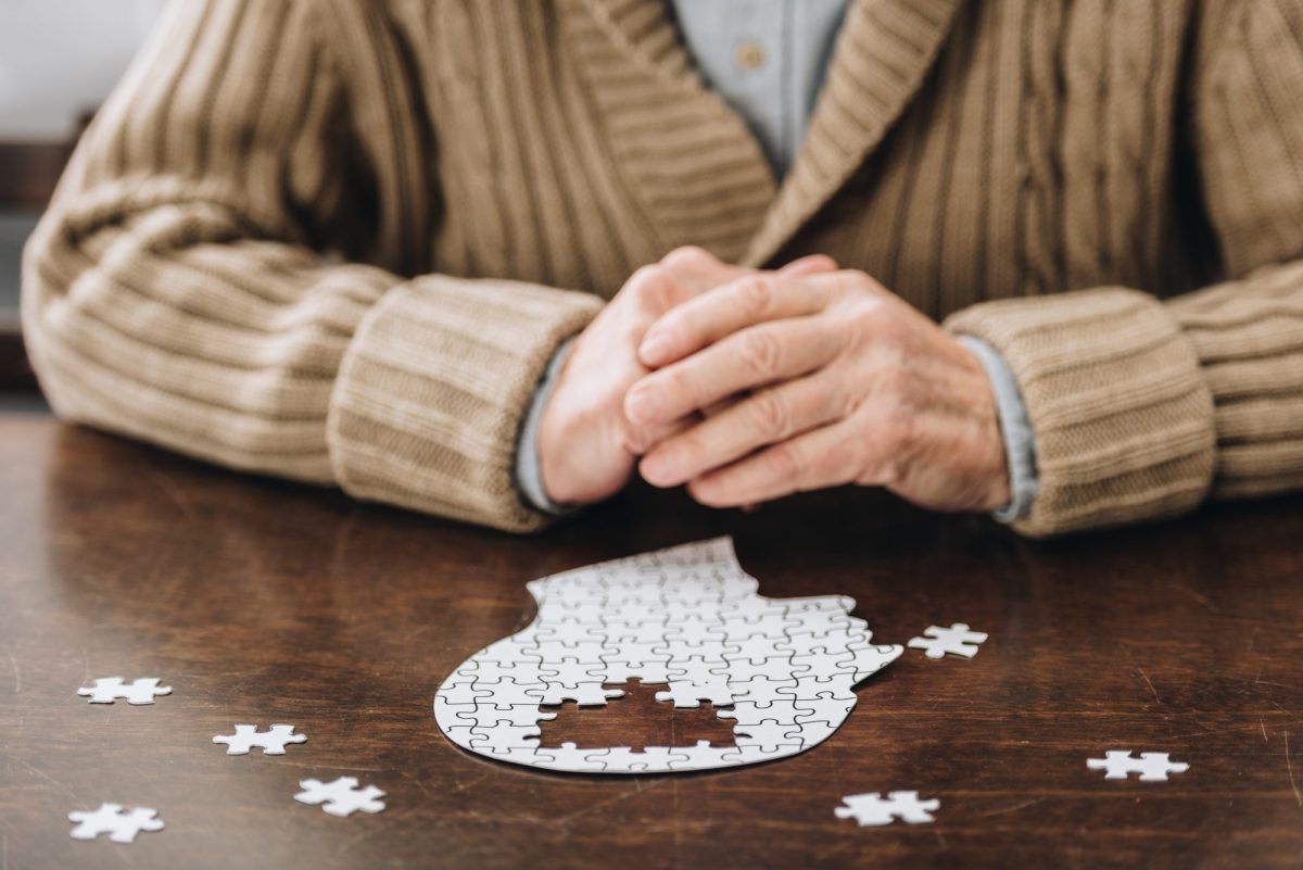 Ältere Mann puzzelt an einem Tisch.