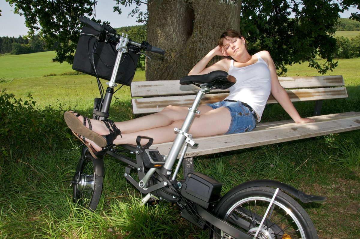 Ein E-Bike als Klapprad, auf dem sich eine Frau ausruht.