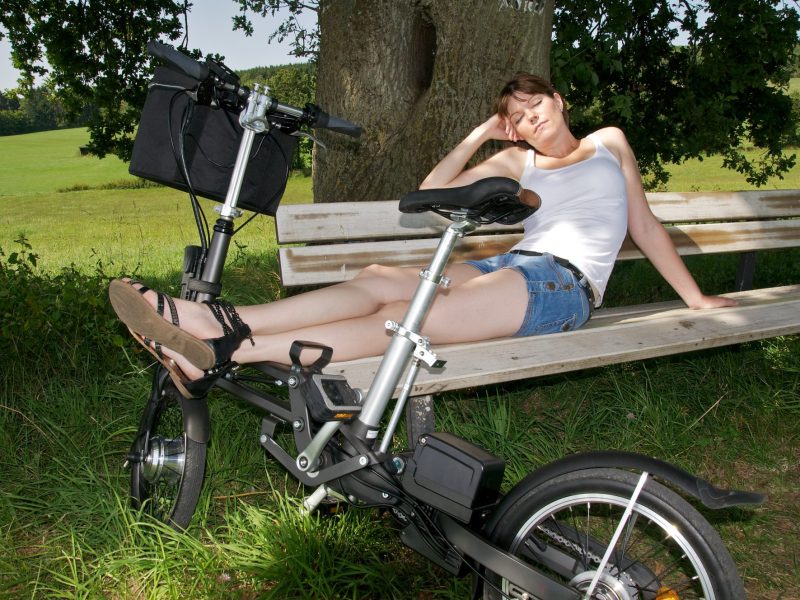 Ein E-Bike als Klapprad, auf dem sich eine Frau ausruht.