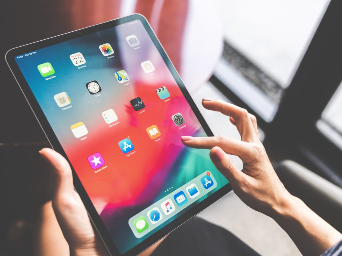 Person hält iPad. Auf dem Display werden verschiedene Apps angezeigt.
