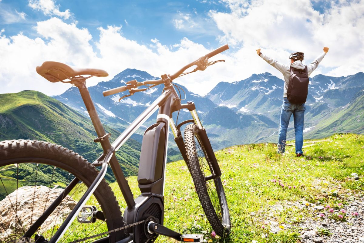 Mann steht neben E-Bike auf einem Berg.