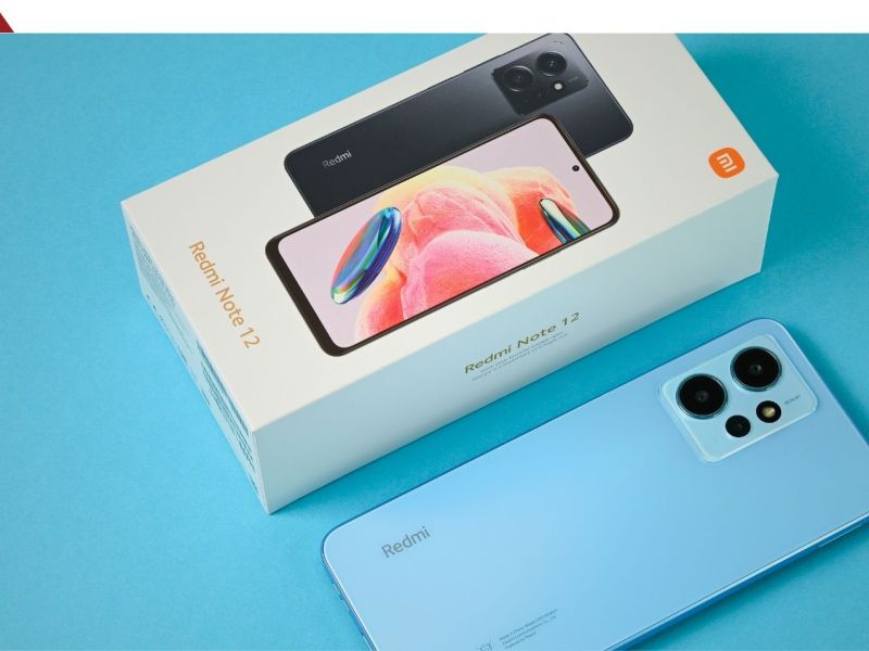 Xiaomi-Handy liegt neben Verpackung auf blauem Hintergrund.