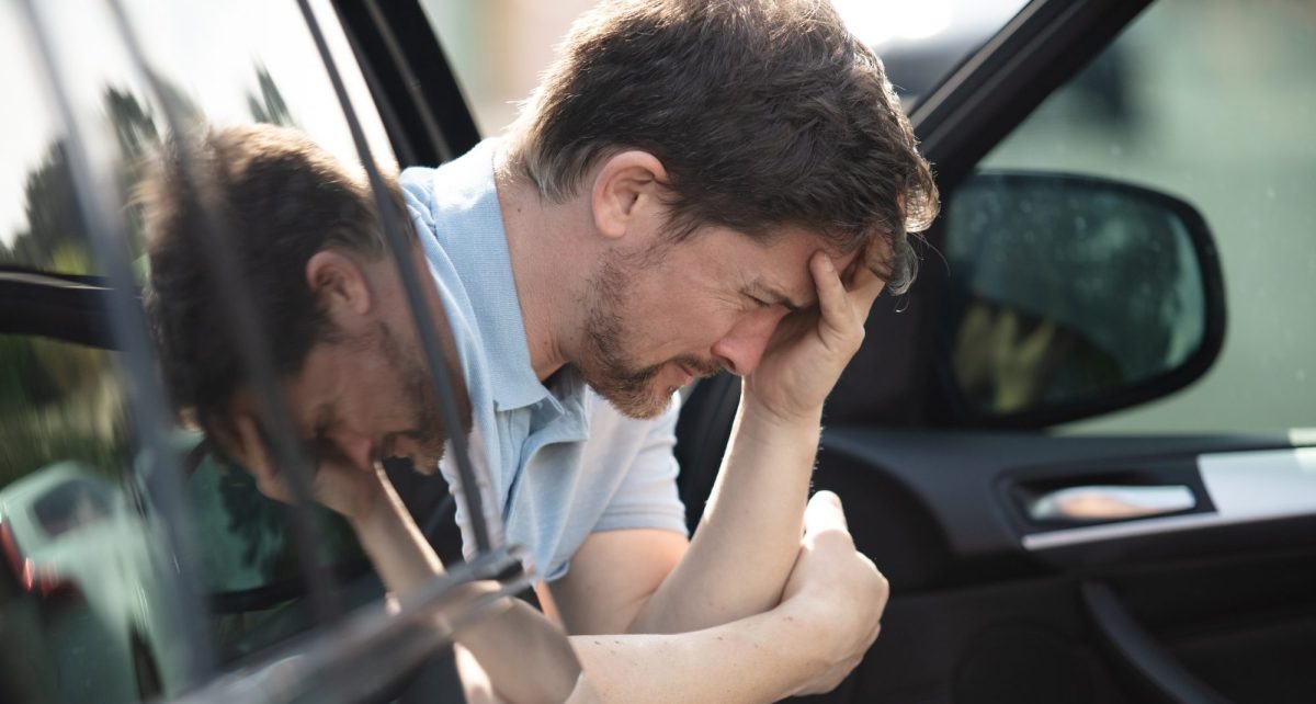 Mann sitzt aufgelöst auf dem Beifahrersitz eines Autos