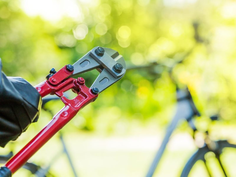 Person mit einem Bolzenschneider vor einem Fahrrad