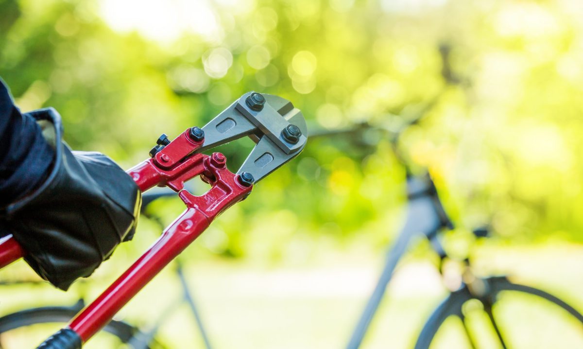 Person mit einem Bolzenschneider vor einem Fahrrad