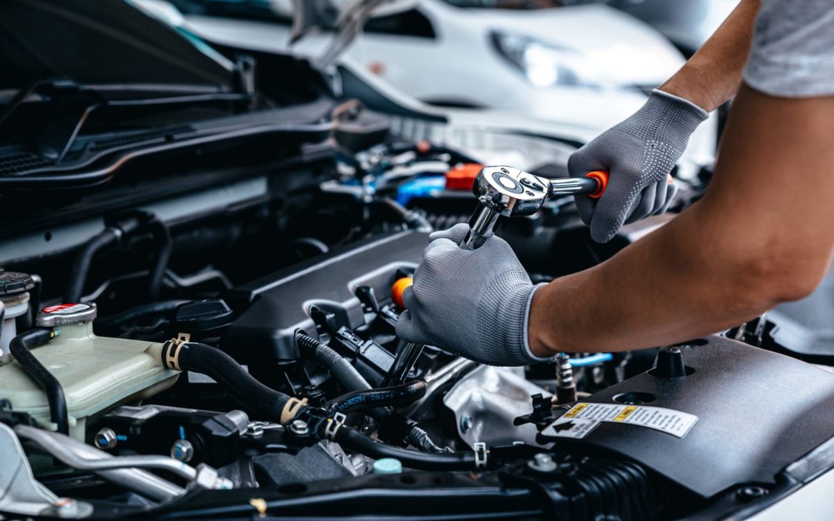 Mann führt Autoreparatur an einem Motor durch.
