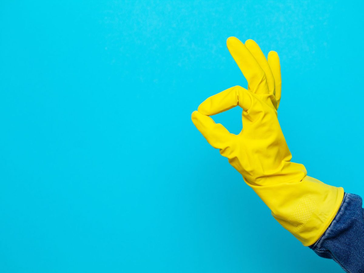 Eine Hand mit gelbem Putzhandschuh.