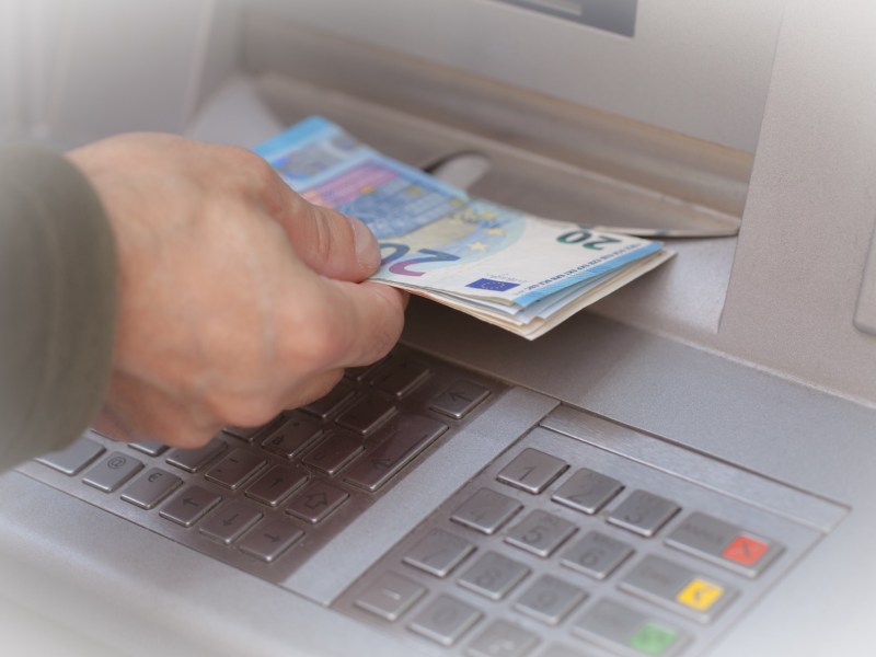 Person hebt Geld am Geldautomaten ab.