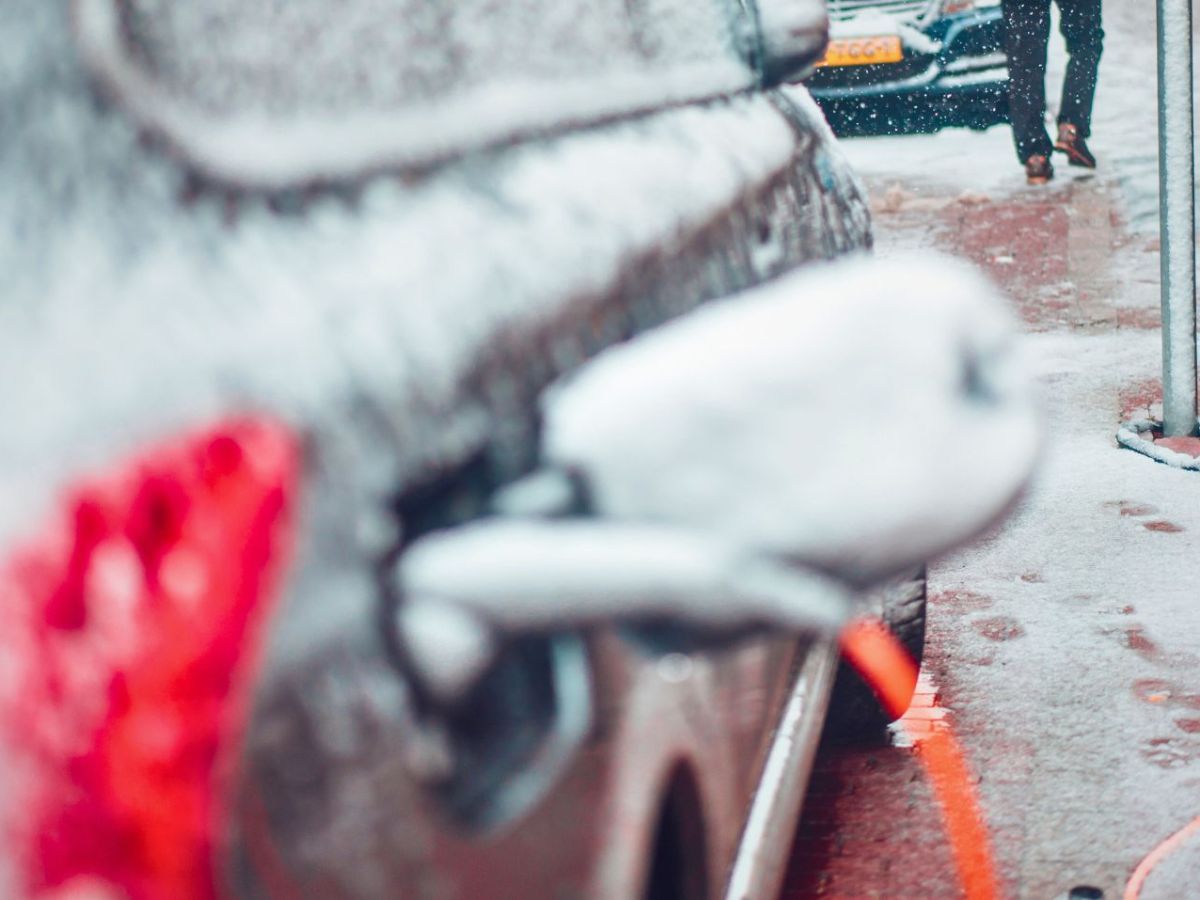 Schneebedecktes Elektroauto an einer Ladesäule
