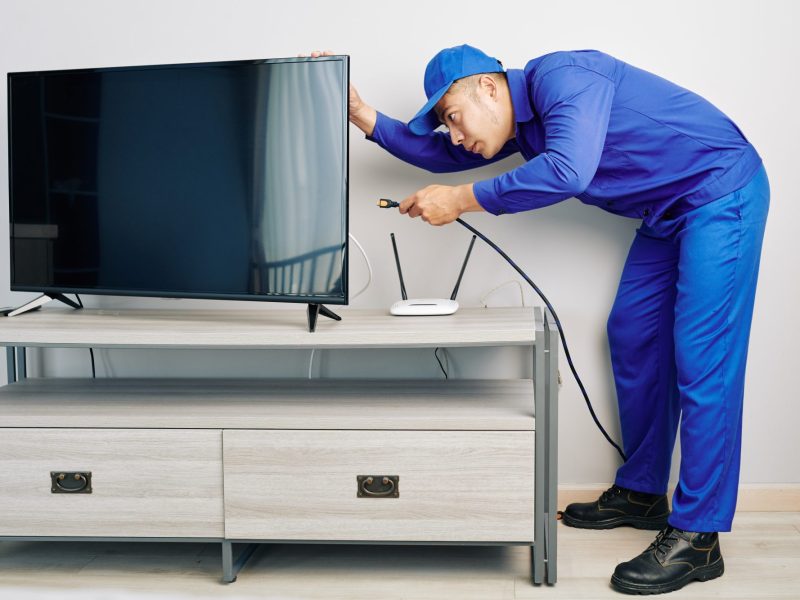 Techniker schließt ein Koaxialkabel an einem TV-Gerät an.