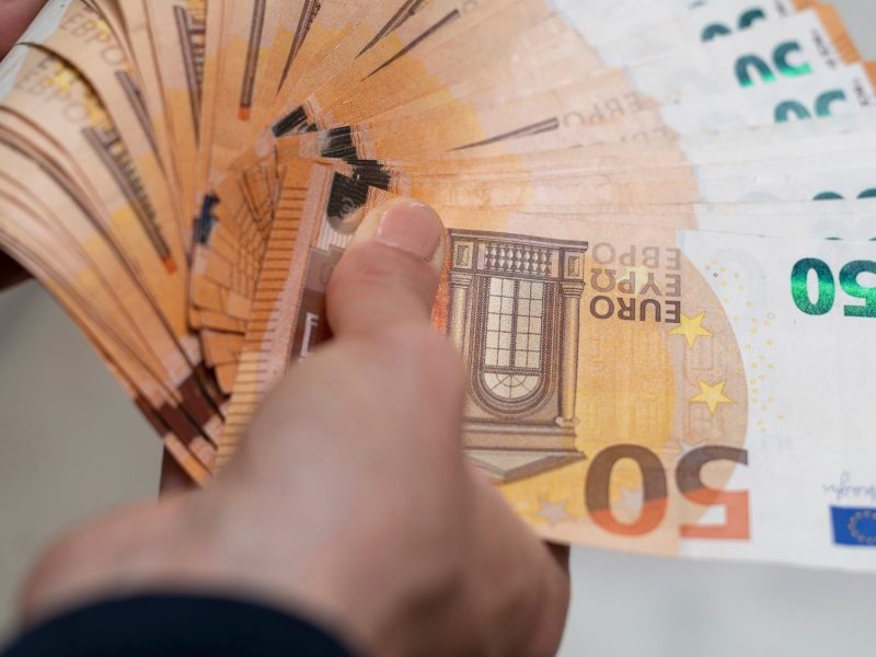 Mnn hält diverse 50-Euro-Scheine in der Hand