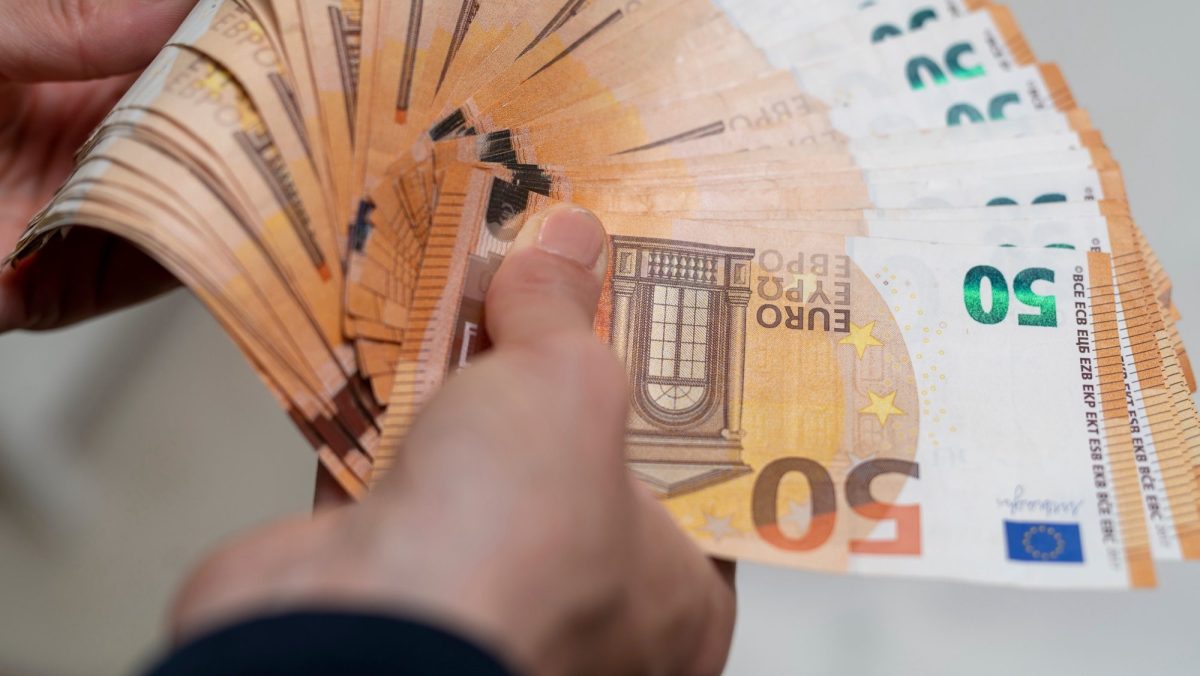 Mnn hält diverse 50-Euro-Scheine in der Hand