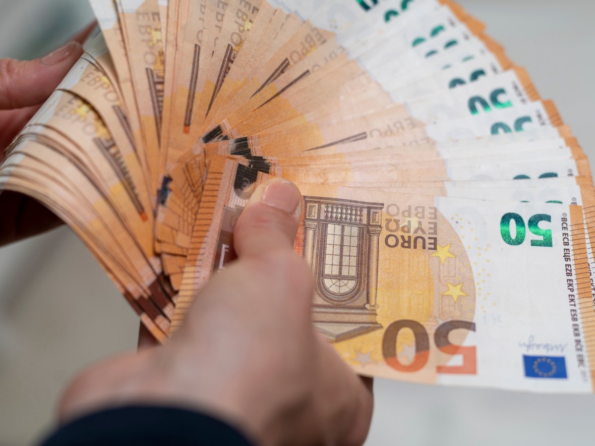 Mnn hält diverse 50-Euro-Scheine in der Hand