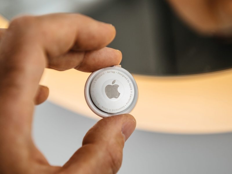 Person hält einen Airtag von Apple in der Hand.