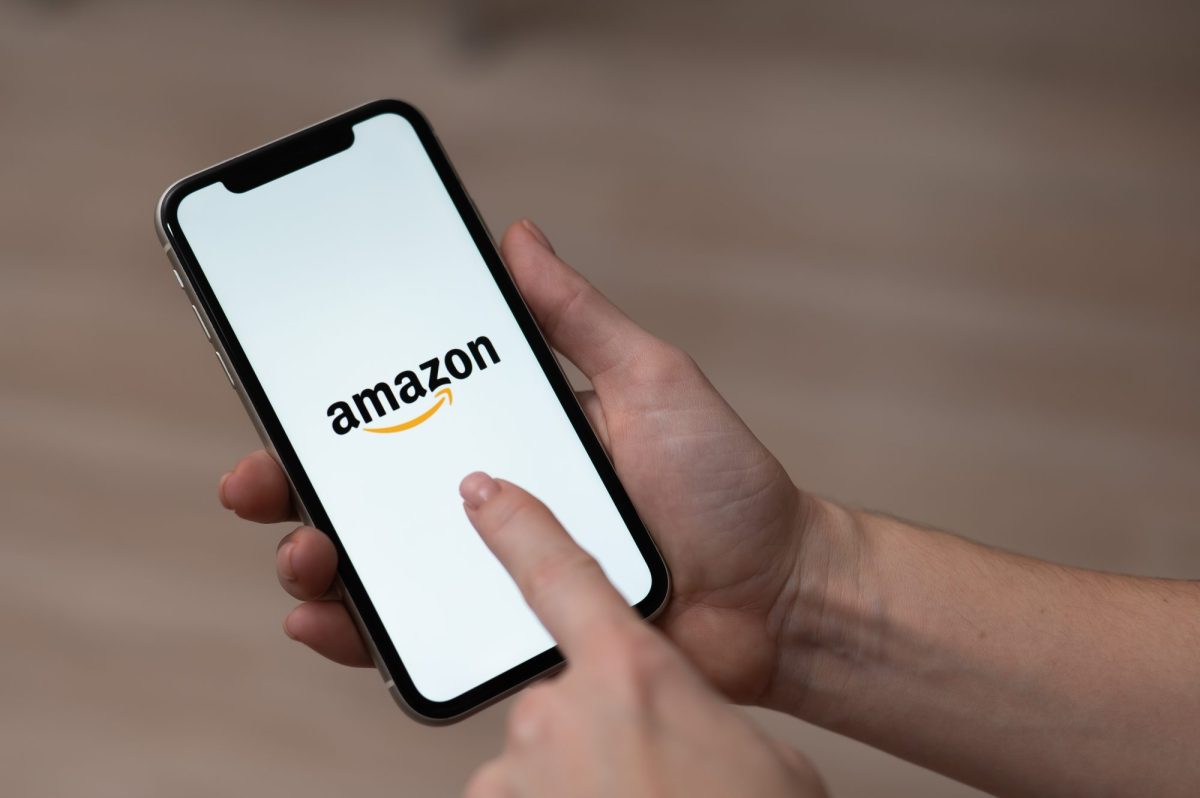 Person hält ein Handy in der Hand. Auf dem Display wird das Amazon-Logo angezeigt.