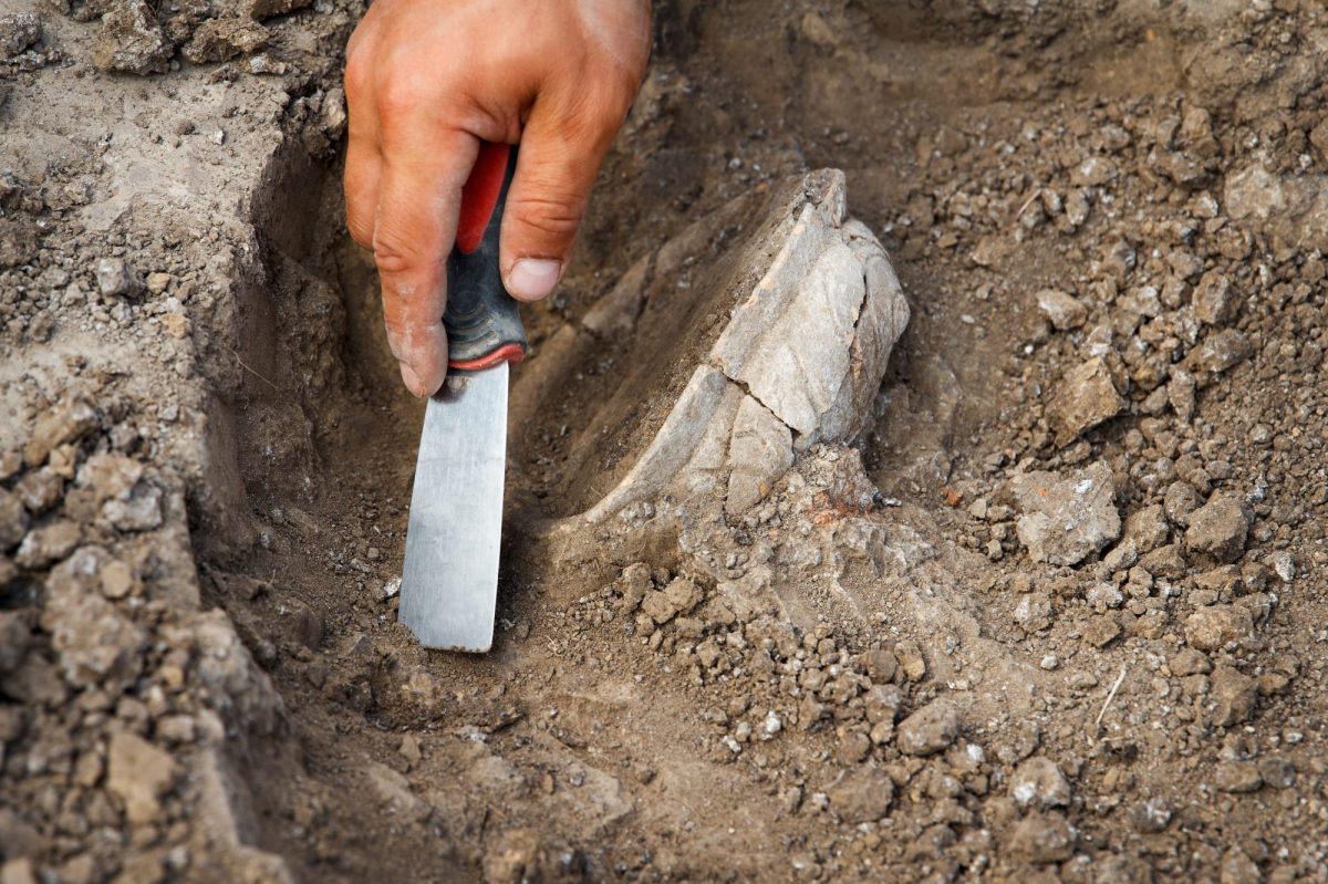 Person arbeitet mit Spaten an einem archÃ¤ologischen Fund.