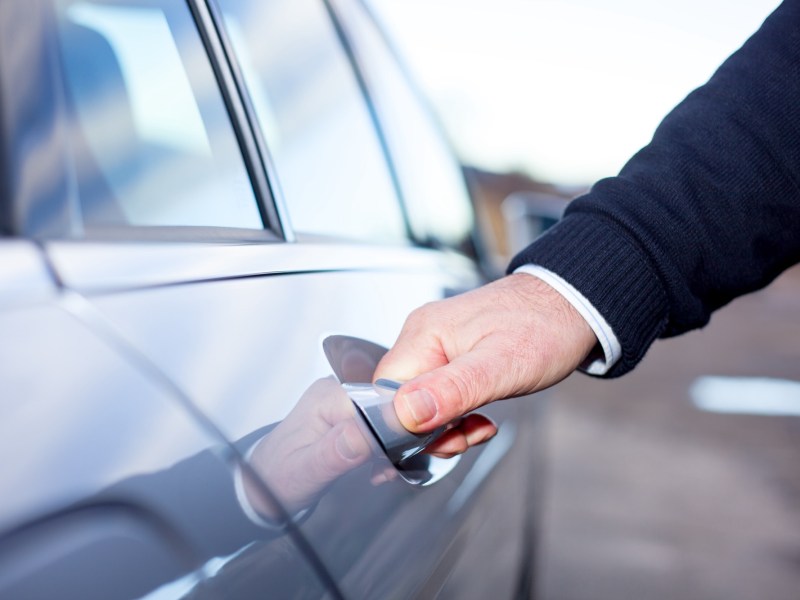 Mann öffnet die Tür am Auto