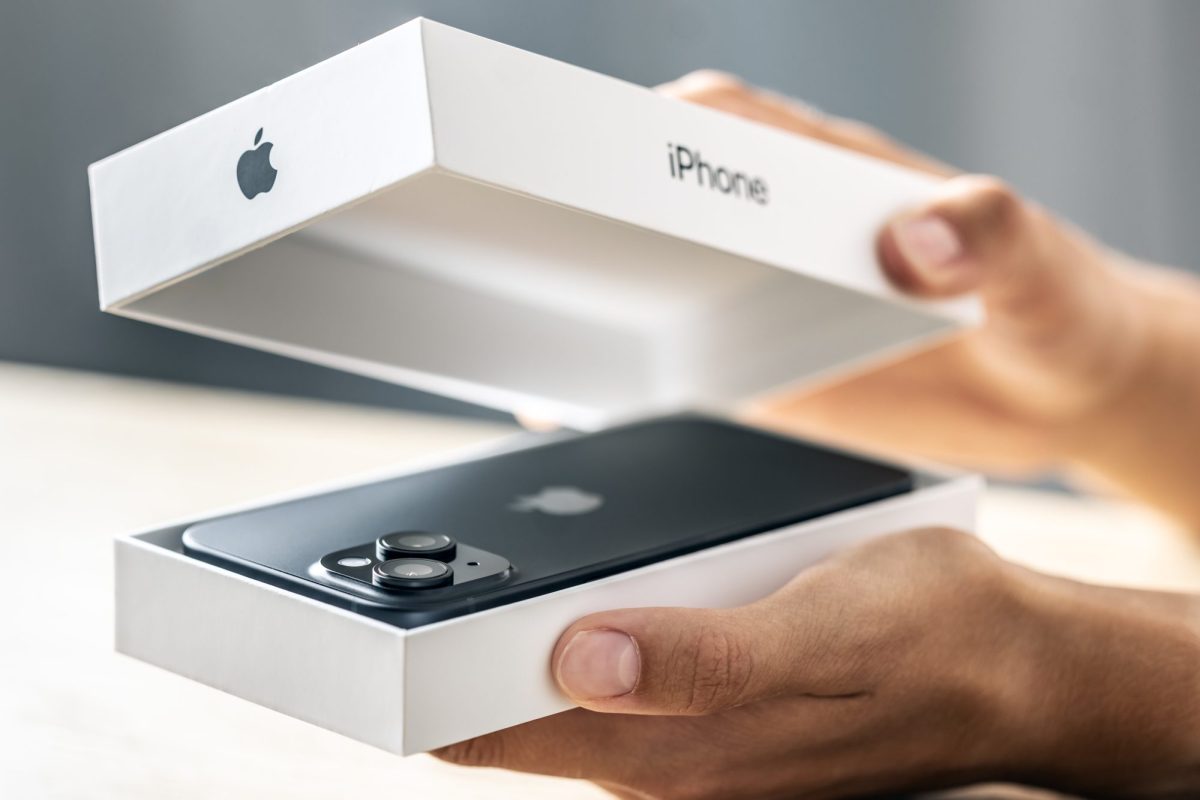 Eine Person öffnet eine Verpackung, in der sich ein iPhone befindet.