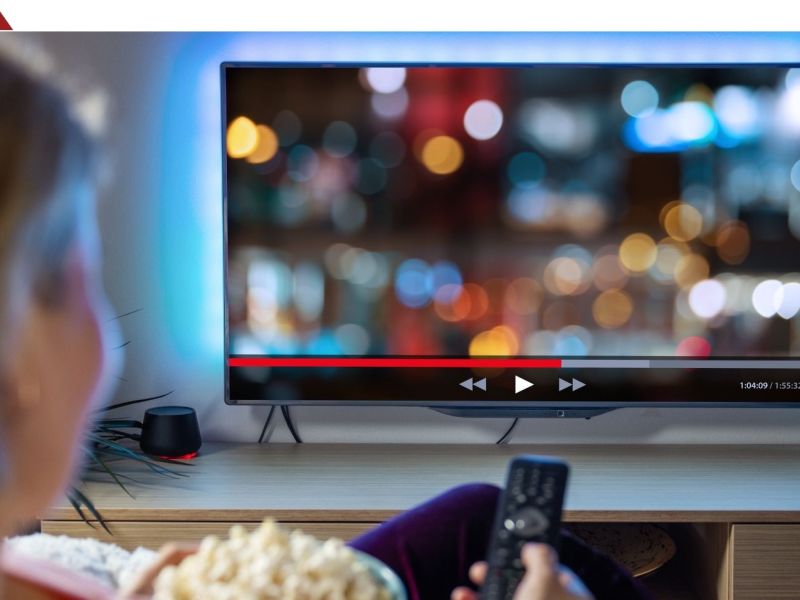 Person sitzt vor dem Fernseher mit einer Schüssel voll mit Popcorn. (Symbolbild)