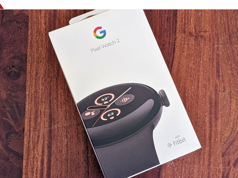 Verpackung einer Google Pixel Watch 2 liegt auf einer Unterlage aus Holz