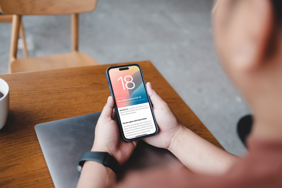 Person hält ein iPhone in der Hand, auf dem iOS 18 geladen ist.