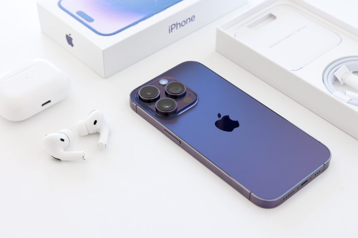 iPhone liegt neben einer Verpackung und Kopfhörer auf einem weißen Untergrund.