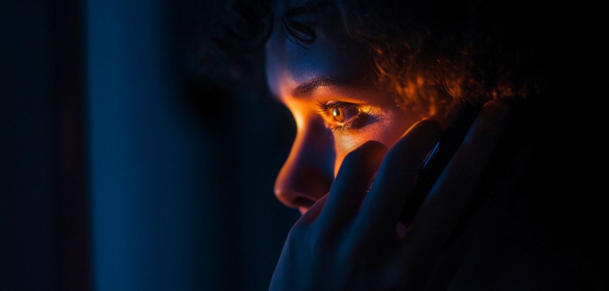 Person mit verzweifeltem Blick hält sich ein Smartphone ans Ohr