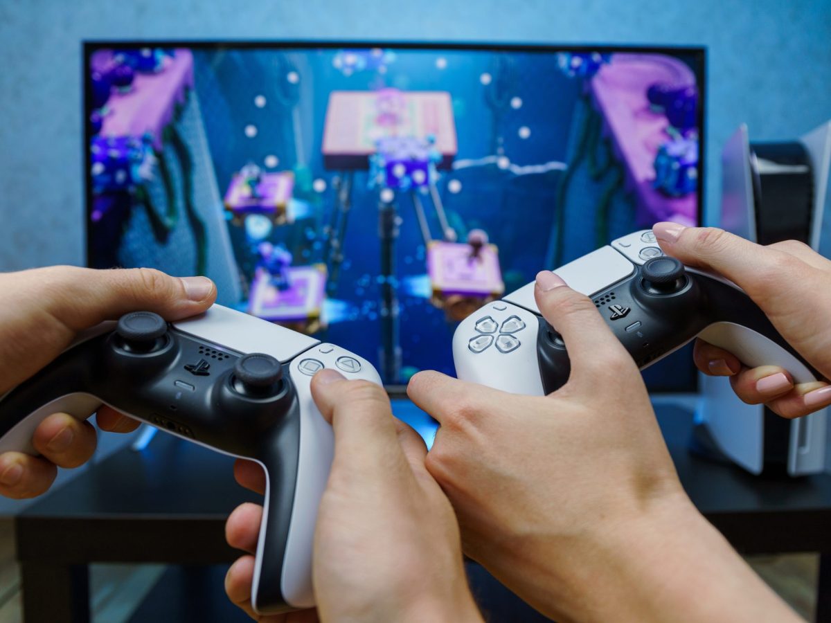 Personen halten PS5-Controller in der Hand und spielen.