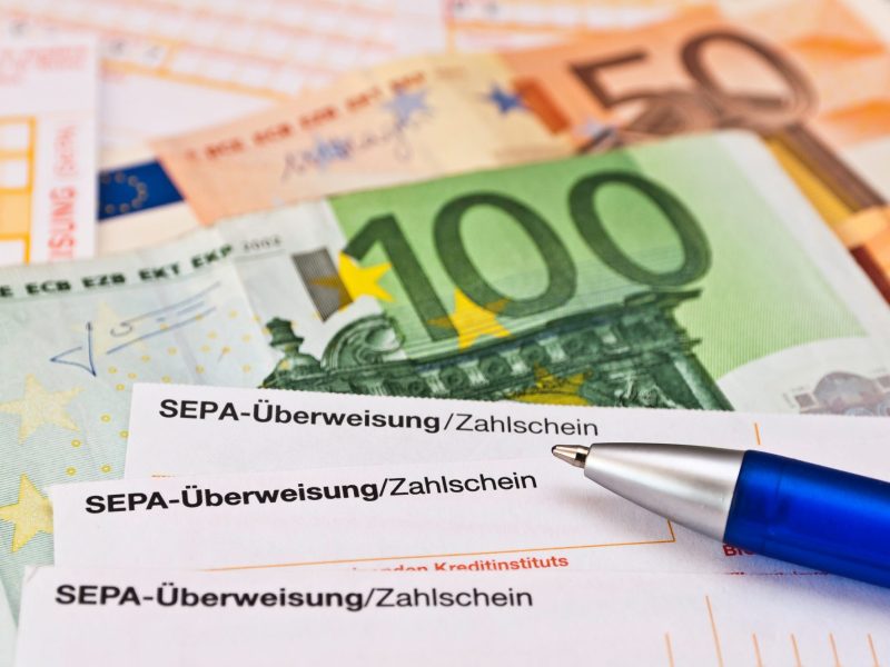 Überweisungsscheine liegen neben Euro-Geldnoten