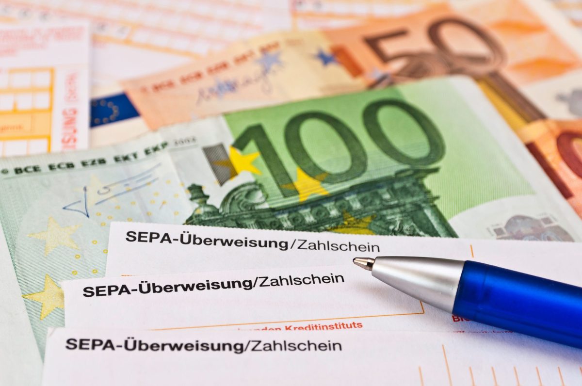Überweisungsscheine liegen neben Euro-Geldnoten