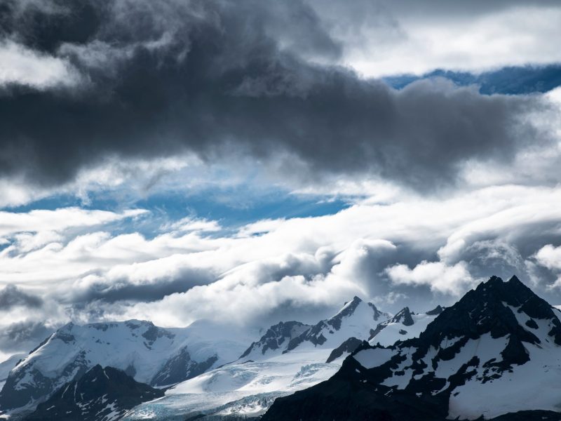 Wolken über schneebedeckten Bergen.