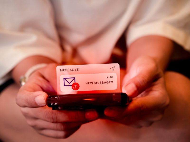 Person hält Handy in der Hand, auf dem eine neue Nachricht eines unbekannten Absenders ankommt.