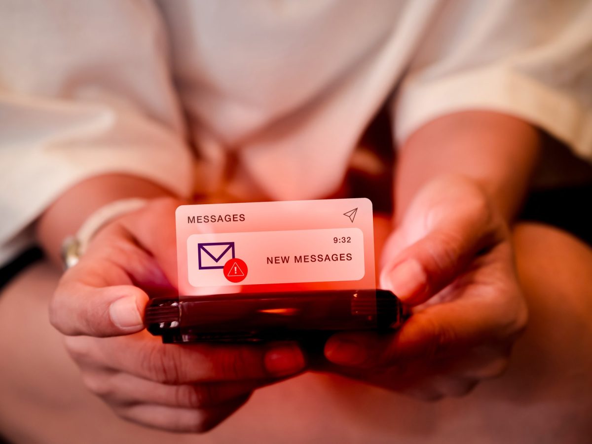 Person hält Handy in der Hand, auf dem eine neue Nachricht eines unbekannten Absenders ankommt.