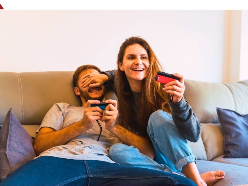 Mann und Frau sitzen auf einem Sofa und spielen mit einer Nintendo Switch