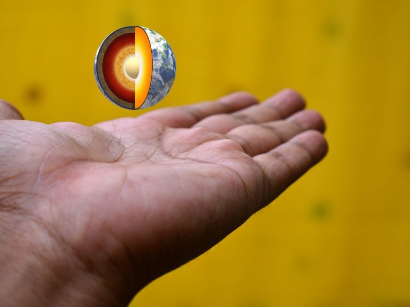 Person hält Hand auf, über der ein kleines Modell der Erde schwebt.