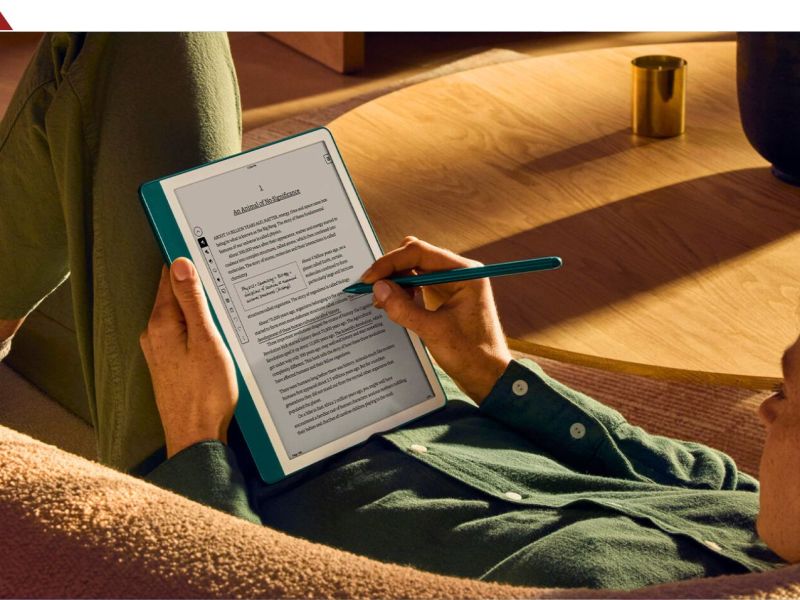 Frau liegt mit einem Kindle Scribe auf dem Sofa