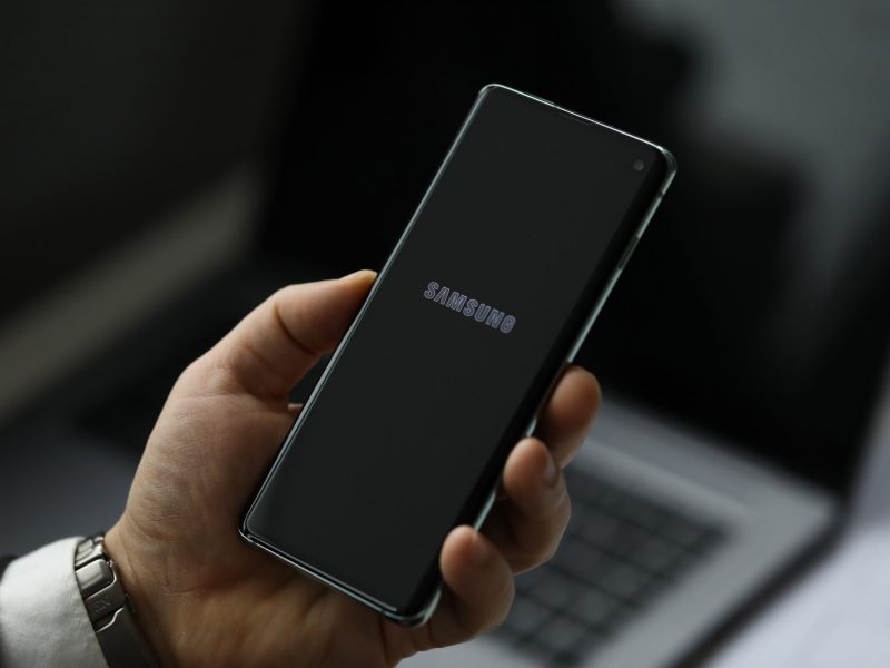 Person hält ein Handy in der Hand. Auf dem Display ist das Samsung-Logo zu sehen.