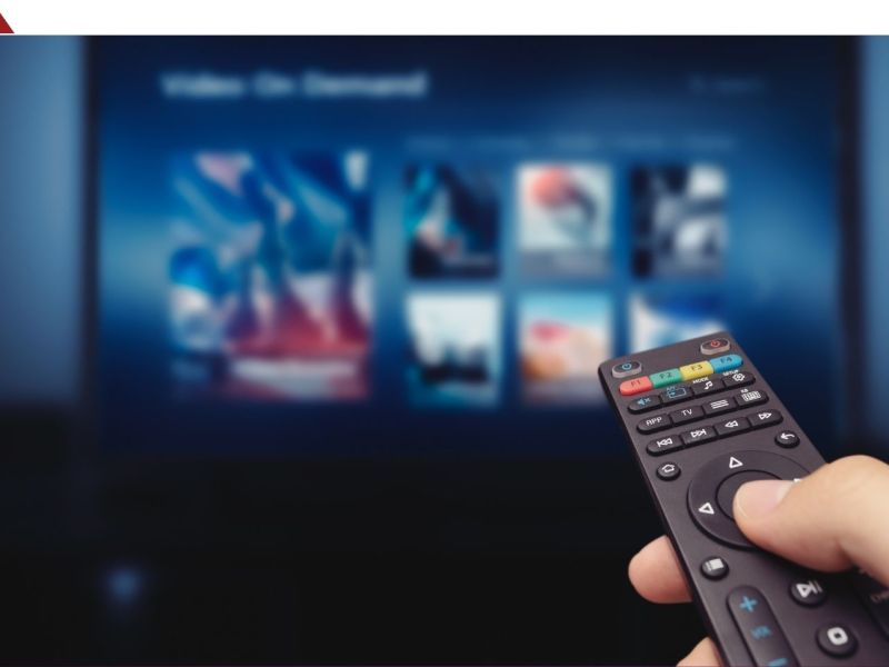 Person hält Fernbedienung in Richtung eines Fernsehers.