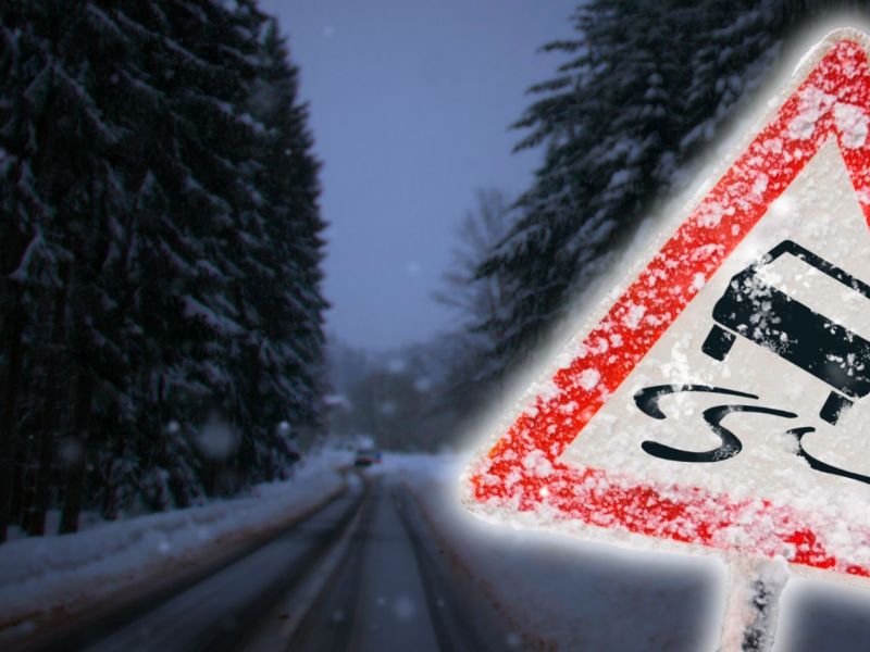 Warnschild vor einer verschneiten Straße