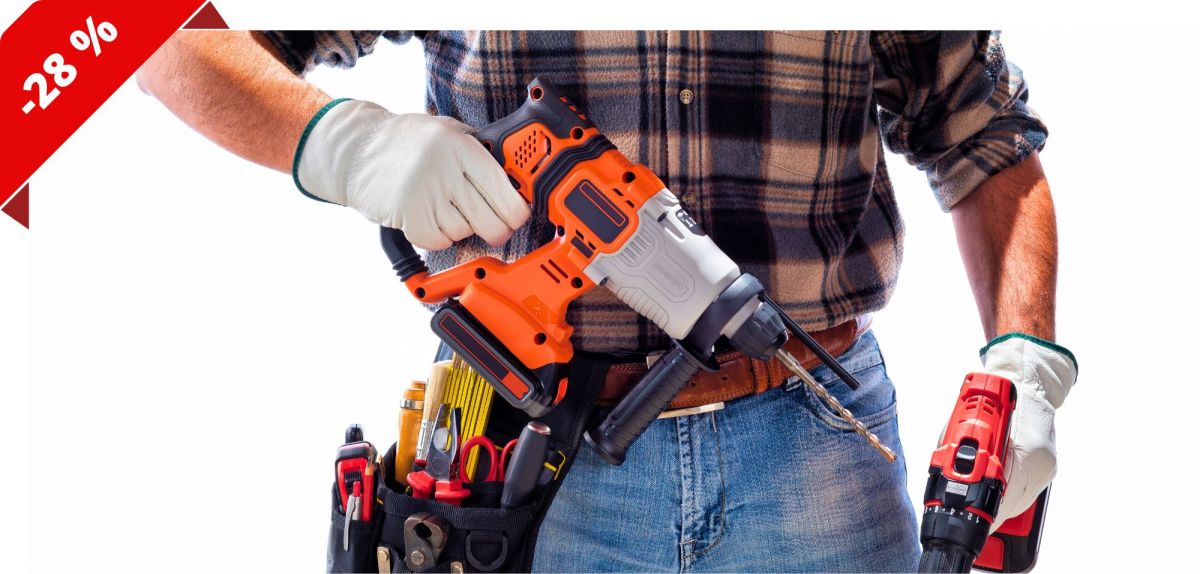 Eine Person mit Werkzeuggürtel hält einen Akku-Bohrhammer in der Hand.