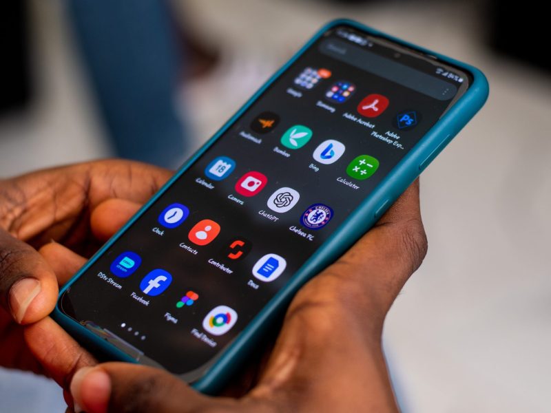 Person hält ein Handy auf dessen Display mehrere Apps angezeigt werden.