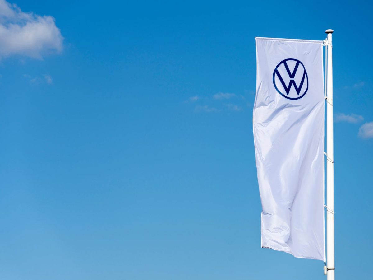 Weiße Fahne mit VW-Logo vor blauem Himmel.