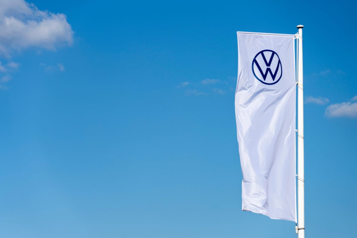 Weiße Fahne mit VW-Logo vor blauem Himmel.