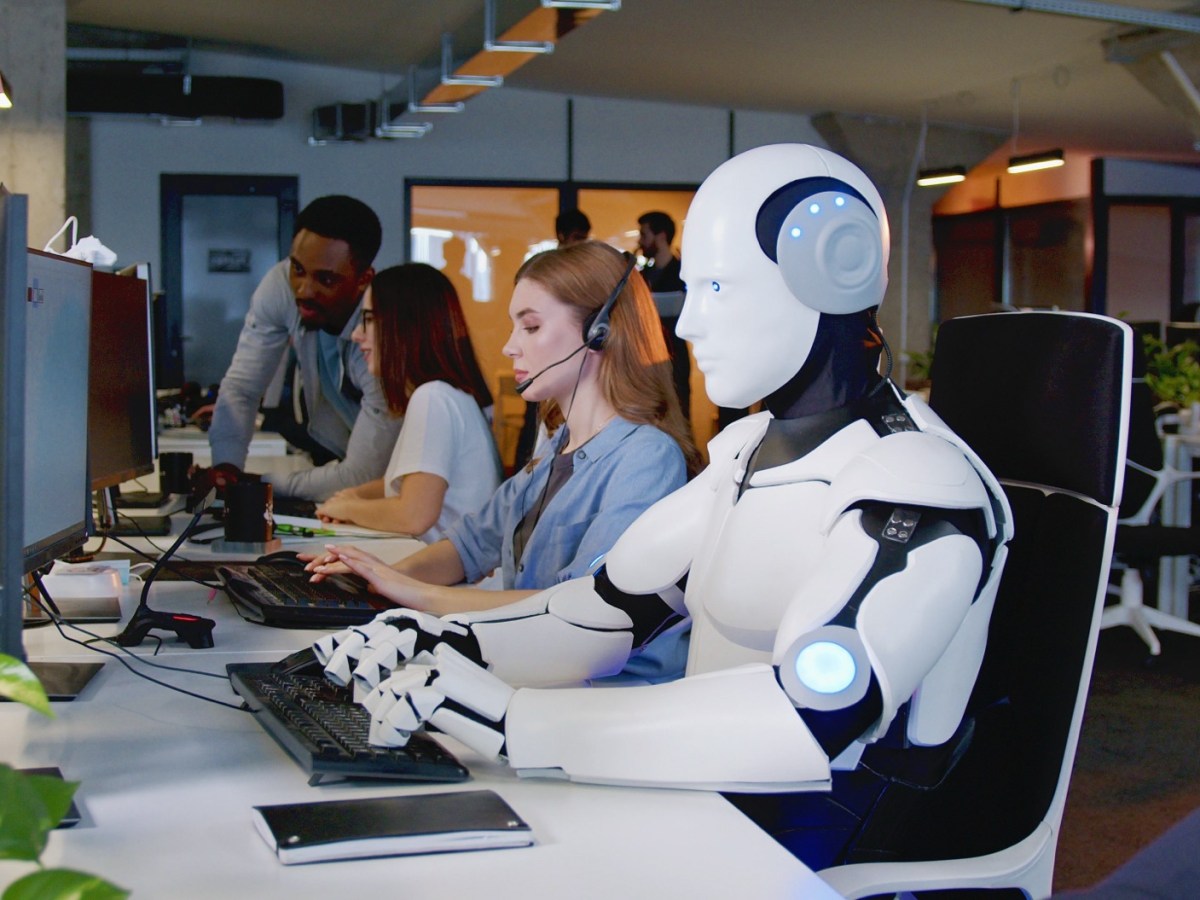 Roboter sitzt im Büro mit Menschen am Tisch